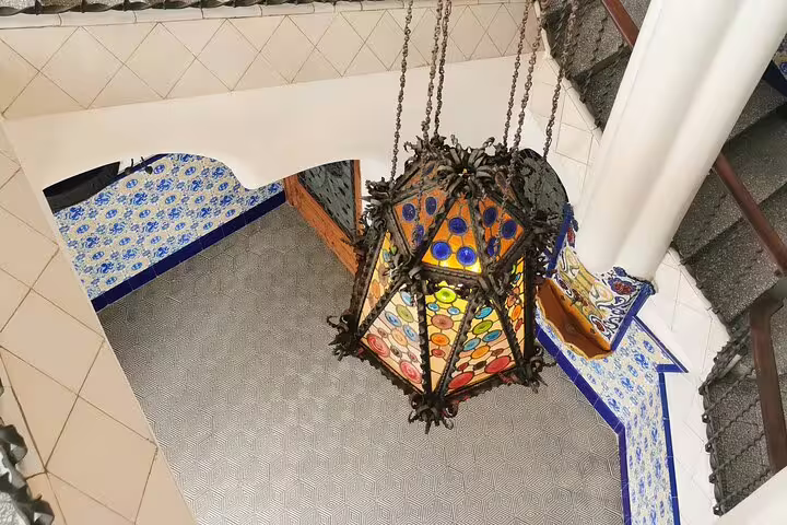 A vibrant stained glass lantern hangs in an ornate interior at Casa Vicens, highlighting Gaudí's architectural brilliance.