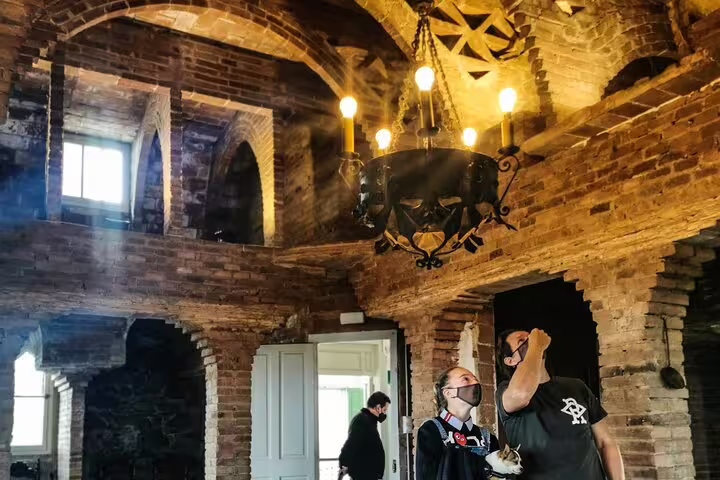 Visitors explore the intricate brickwork and arches of Colonia Güell during a private, skip-the-line tour of Gaudí's architecture.