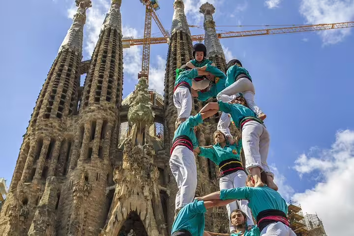 Participants in traditional Catalan human tower in front of Sagrada Familia, part of a 2-day Gaudi, Montserrat, and Winery tour.