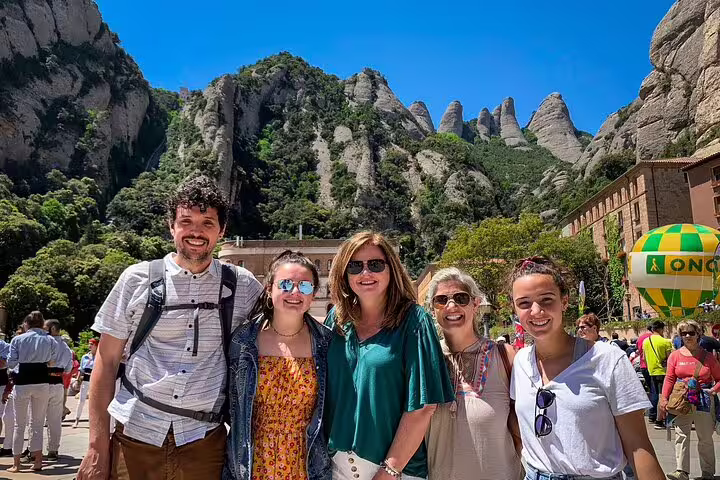 Group of tourists enjoying a sunny day at Montserrat with scenic mountain views, part of the 2-Day Gaudi and Winery Tour.