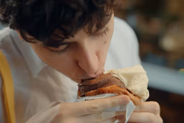 Individual savoring a chocolate and vanilla gelato in a pastry, capturing the indulgence of Florence's gelato tour.