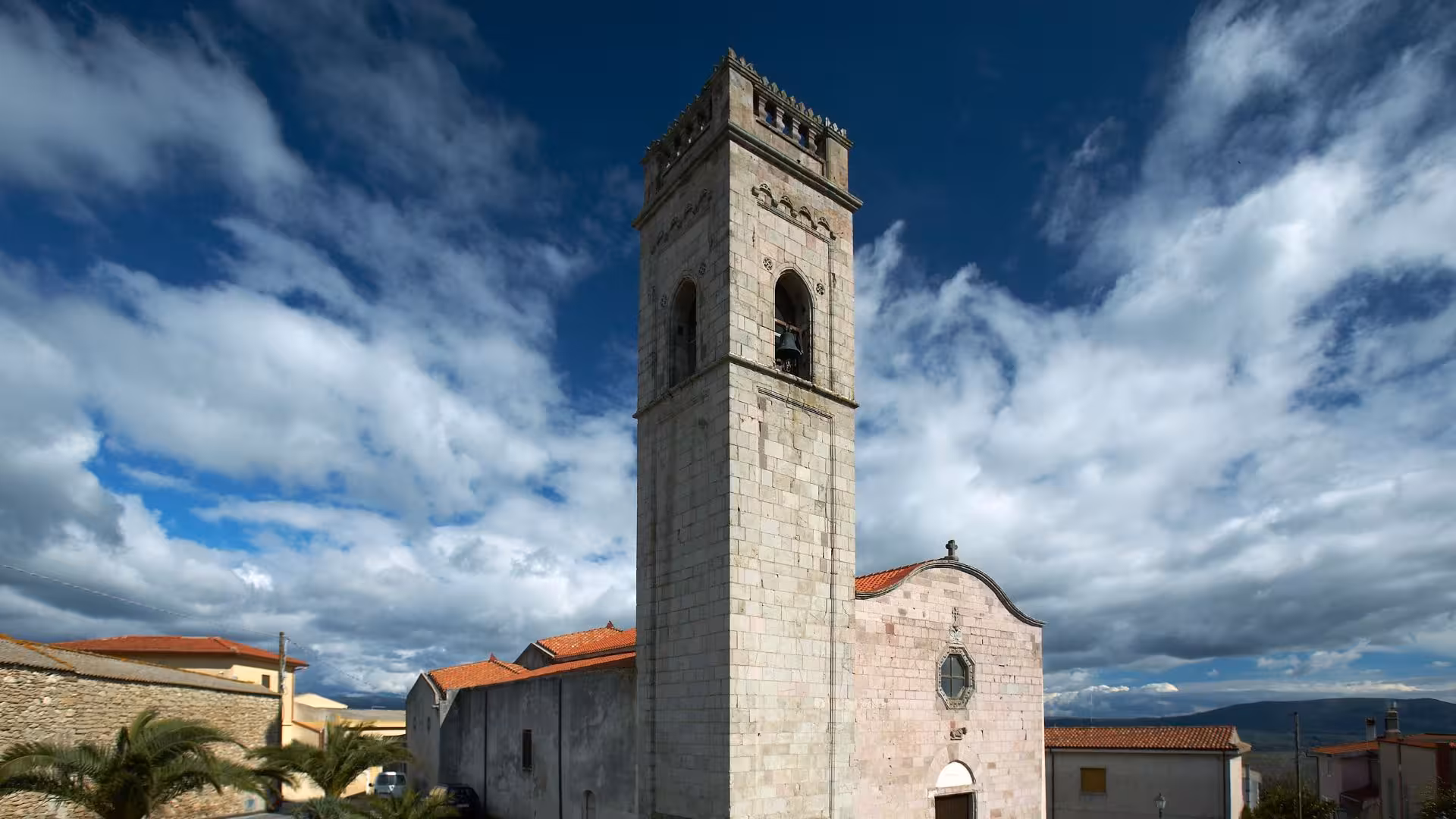 Historic stone church tower against a dramatic sky, a highlight of Genoni's cultural and architectural heritage.