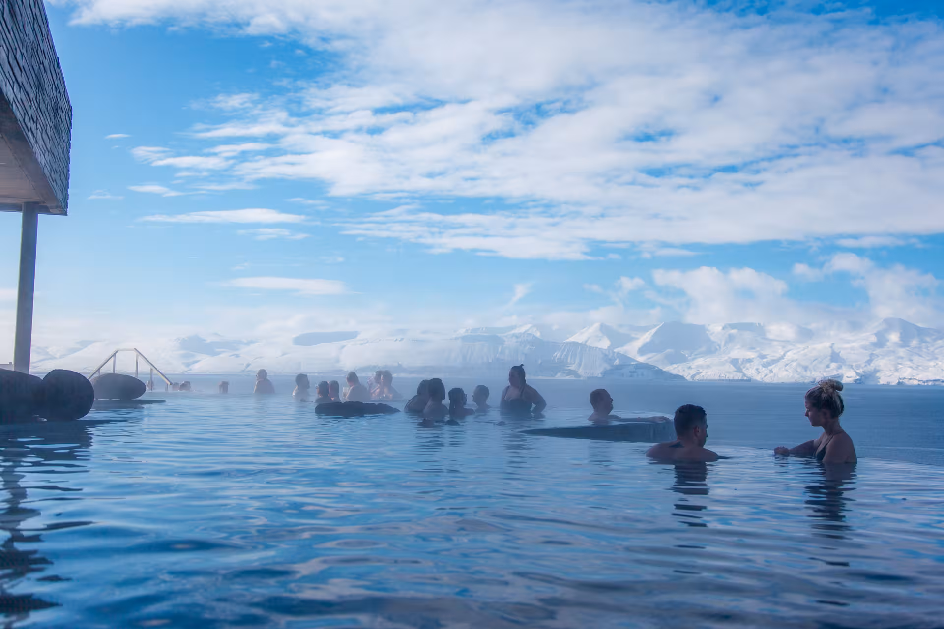 Visitors enjoy the relaxing GeoSea Geothermal Baths with a backdrop of snowy mountains in Iceland.