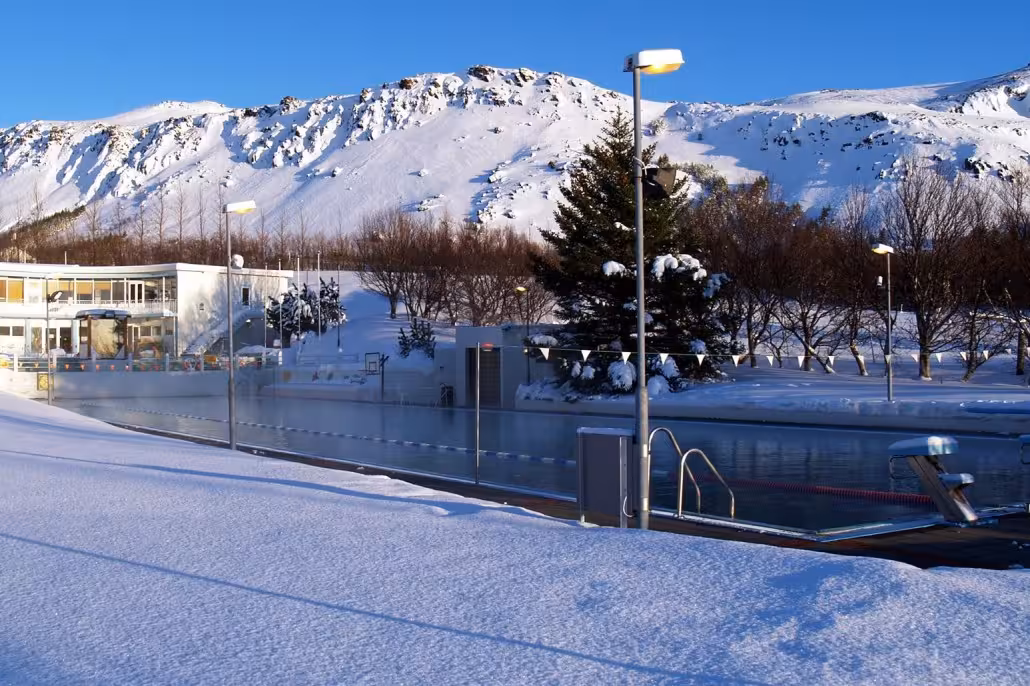 Geothermal spa pool in snowy Iceland with mountain backdrop, perfect post-ride relaxation on the 05C tour