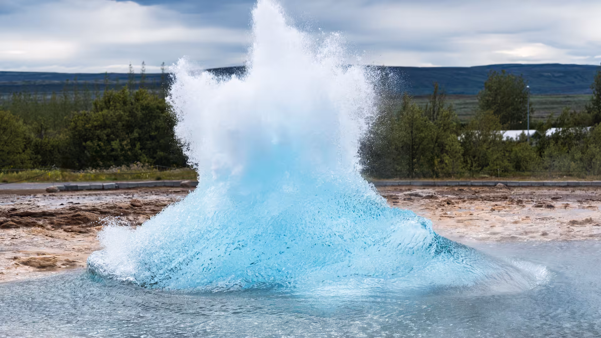 Geysir geothermal area in Iceland erupting with vibrant blue water, a highlight of the Golden Circle tour.