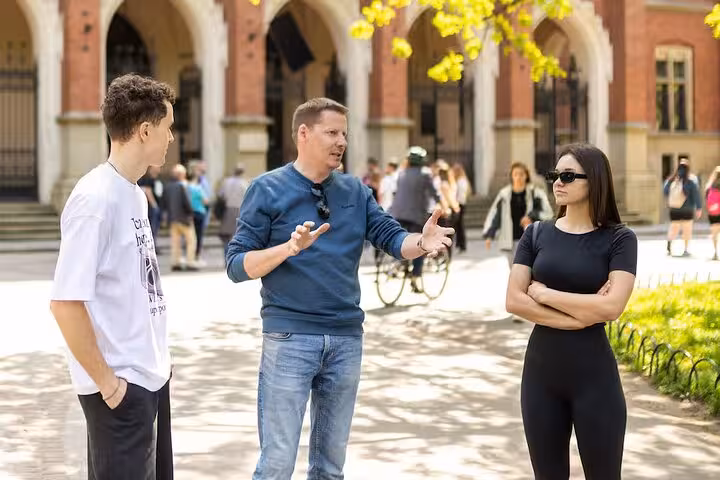 Tour guide explaining WWII history to visitors on a sunny day near historical arches on a Ghetto Walking Tour.