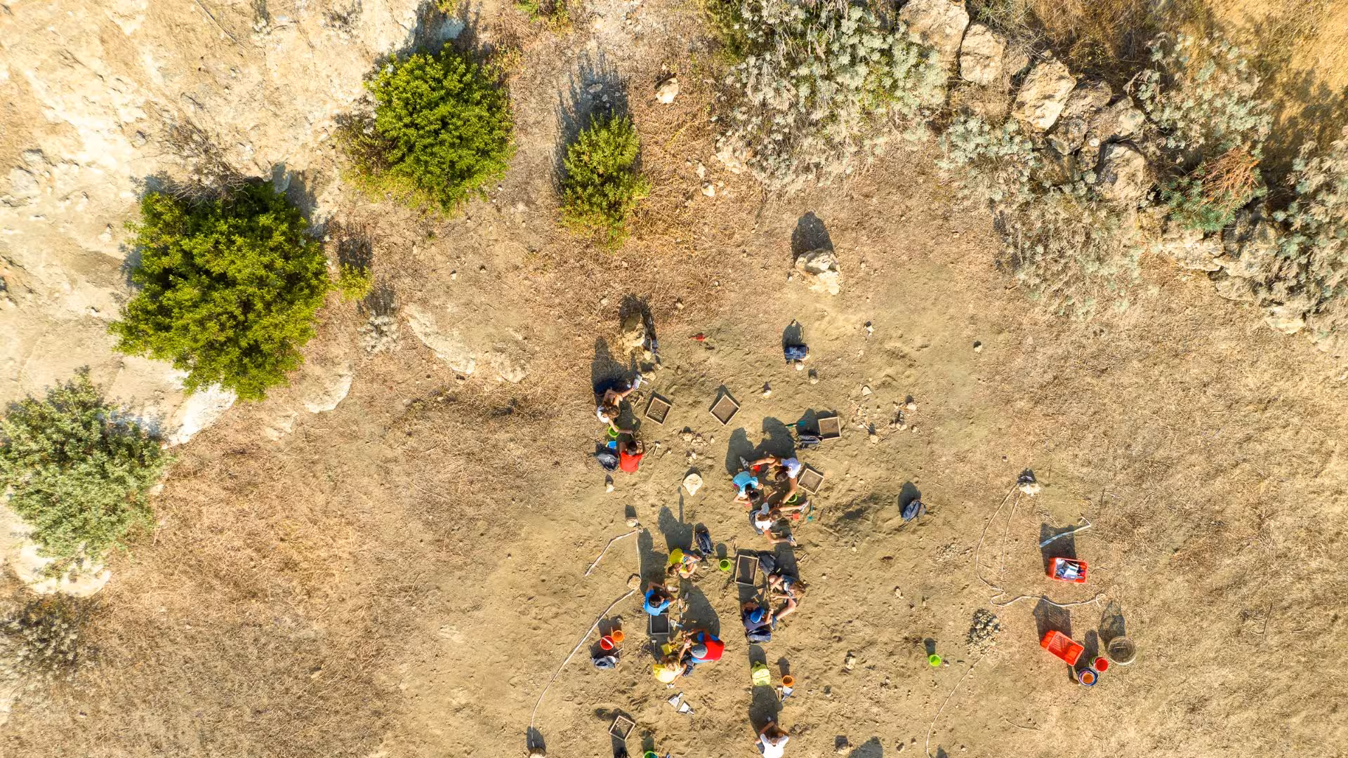 Aerial shot of an archaeological dig site in Giara Park, with people engaged in exploration activities.