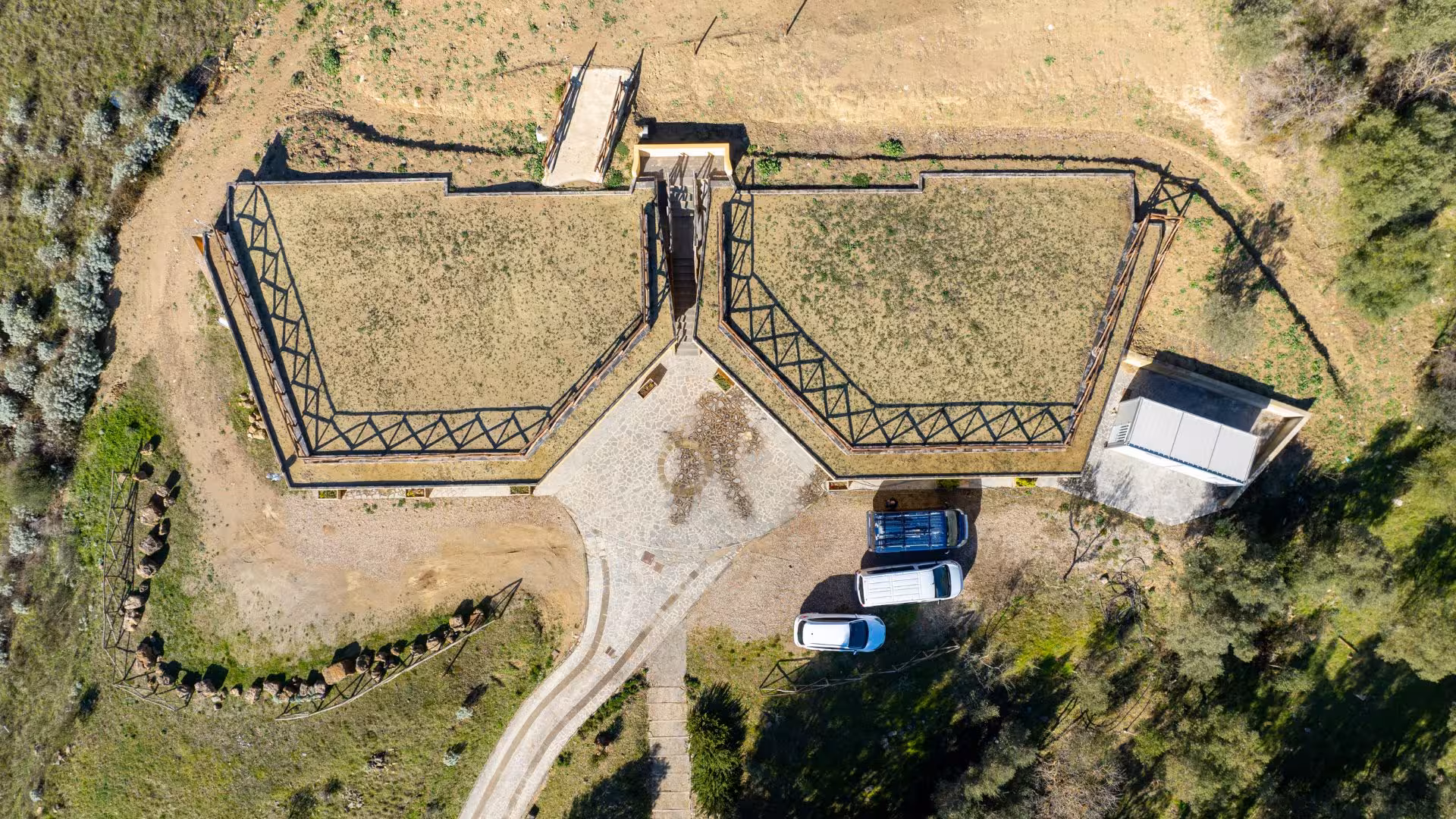 Aerial view of Giara Park entrance with geometric pathways and parked vehicles, showcasing its natural landscape.