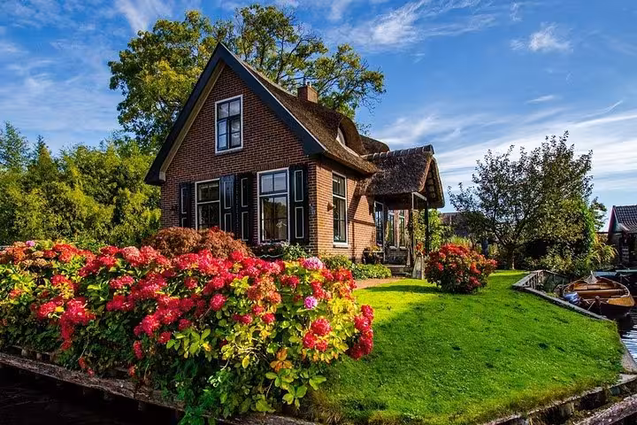 Giethoorn private tour view of thatched cottage and vibrant gardens beside canal, Netherlands boat trip