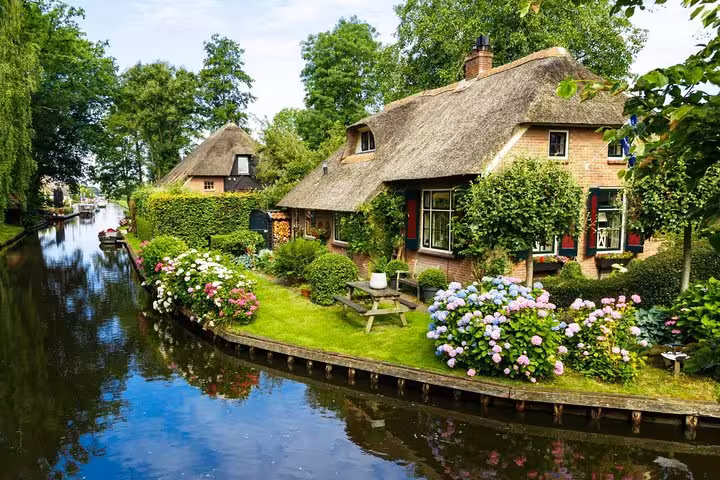 Thatched-roof cottage and hydrangea garden beside Giethoorn canal, scenic stop on private tour and boat trip