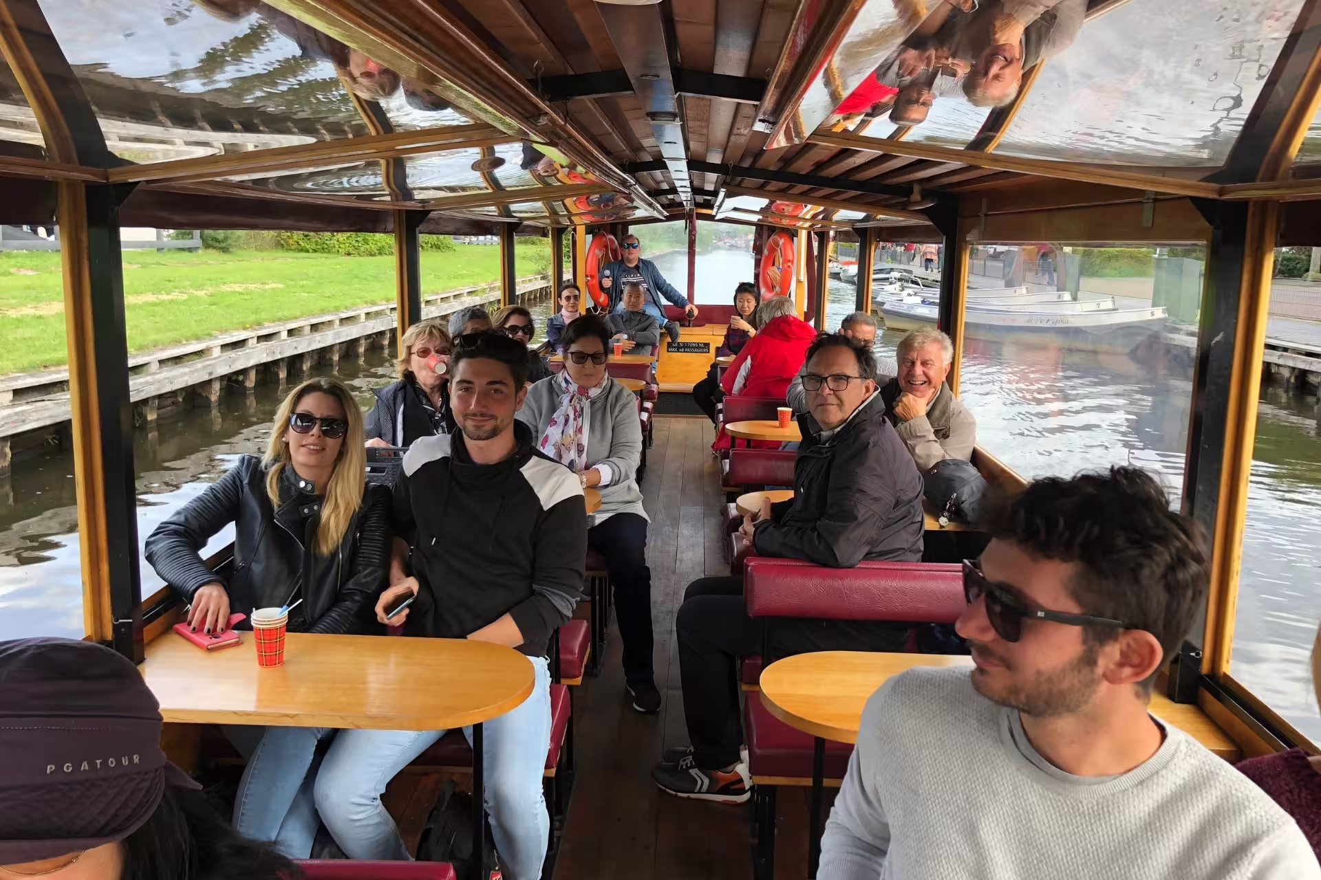 Passengers enjoying a Giethoorn canal cruise boat ride on Amsterdam day tour to Giethoorn and Zaanse Schans