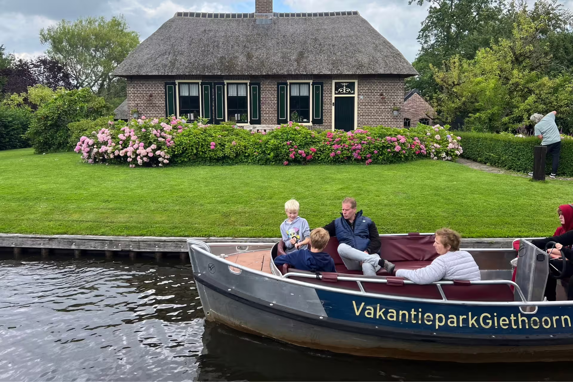 Giethoorn canal cruise boat by a thatched farmhouse and hydrangeas on Amsterdam day trip excursion