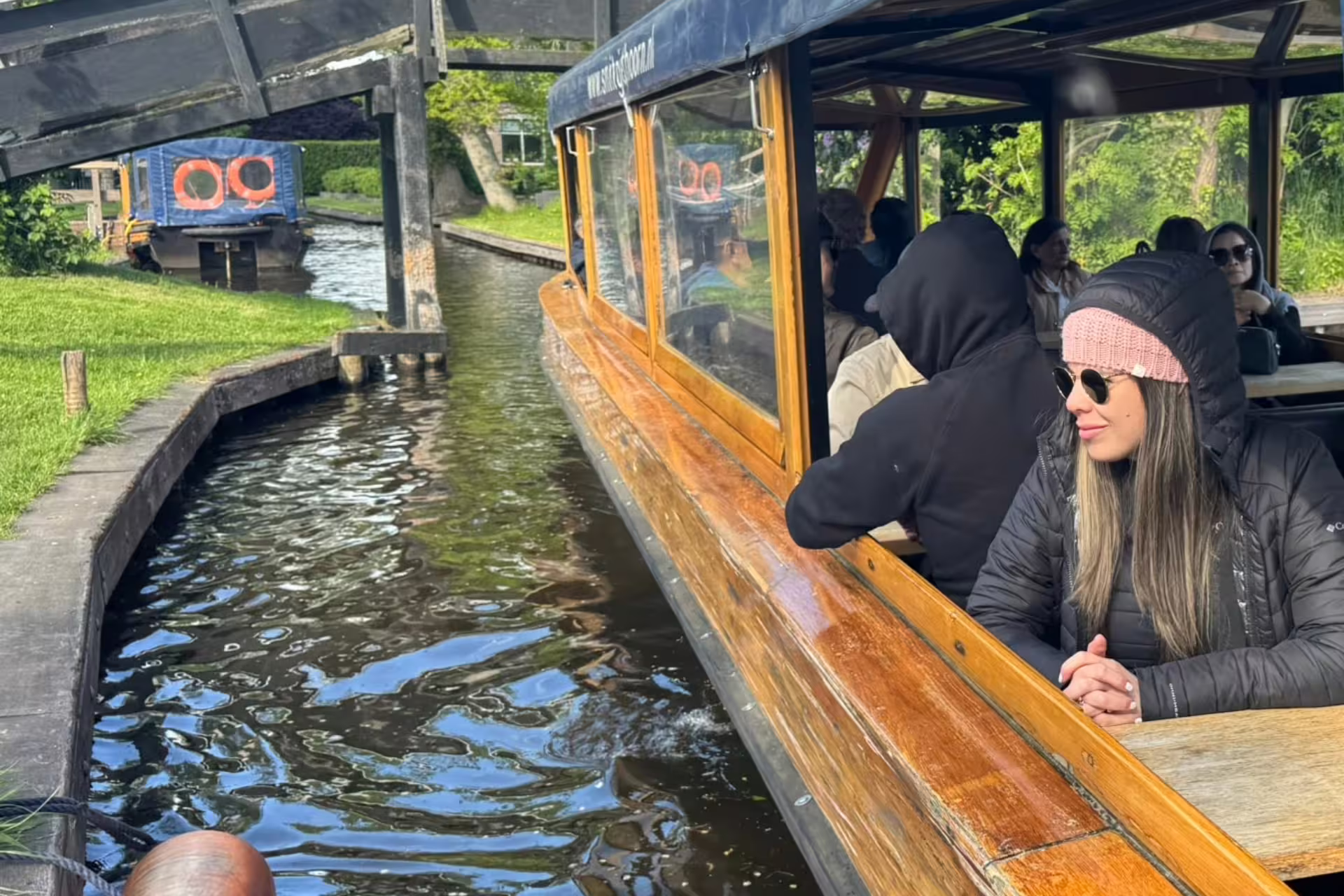 Giethoorn canal cruise boat passing under a wooden bridge, included on Amsterdam day trip tour