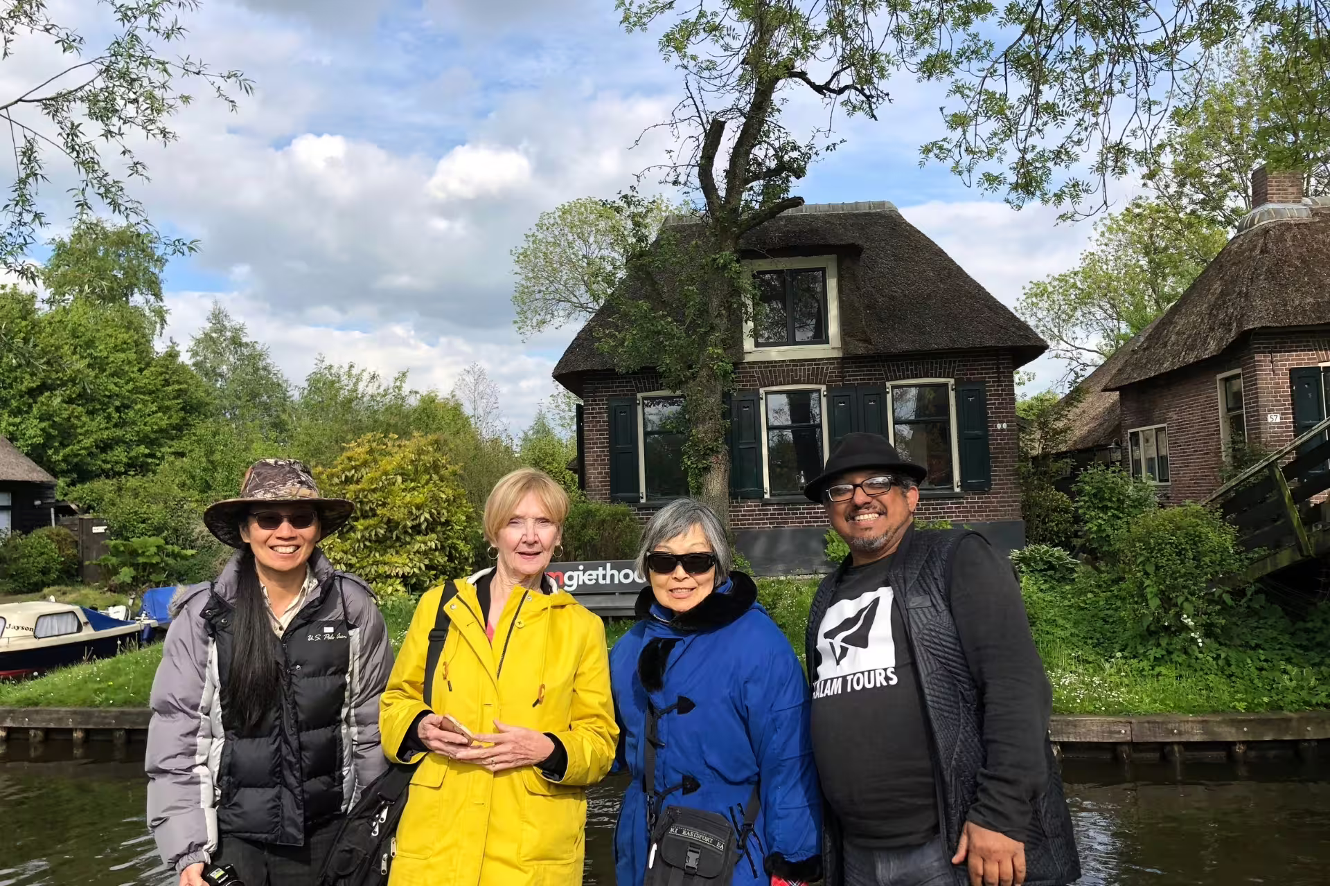Giethoorn canal-side photo with travelers by thatched farmhouse, Amsterdam Zaanse Schans Volendam tour