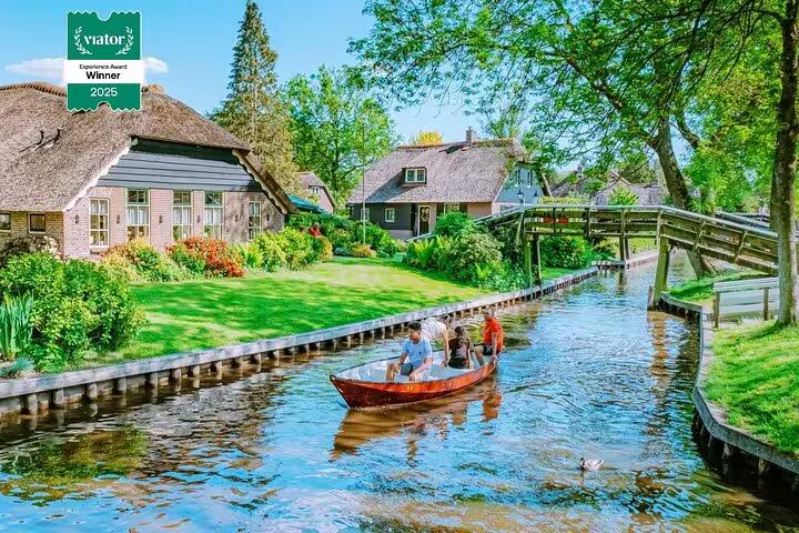 Private Giethoorn tour boat trip on canal past thatched cottages and wooden bridge in Dutch village