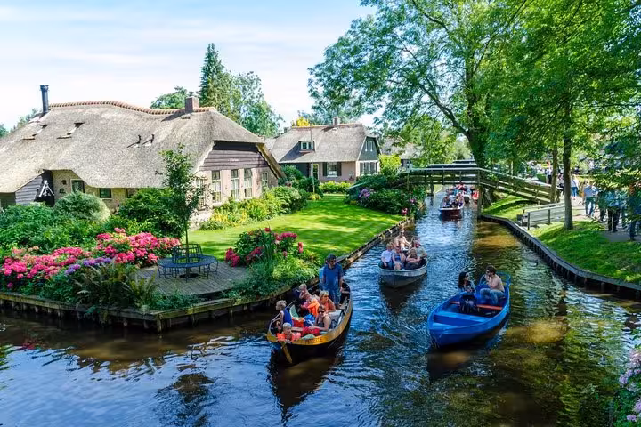 Giethoorn private canal cruise with small boats passing thatched houses, flower gardens and arched bridges