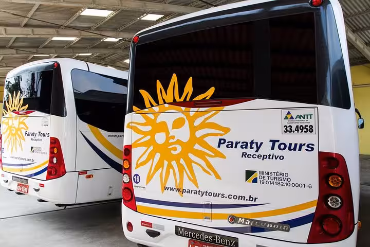 Two Paraty Tours shuttle buses parked, featuring vibrant sun logo, ready for exclusive Rio de Janeiro hotel transfers.