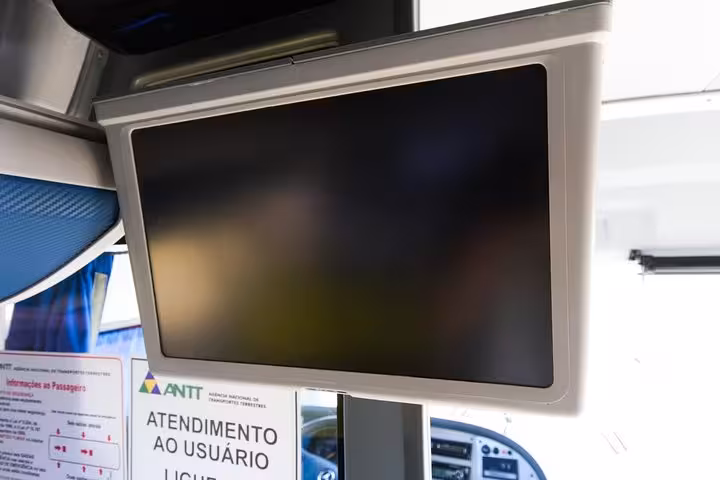 Interior view of a Rio shuttle bus with a screen displaying passenger information for a comfortable airport transfer.