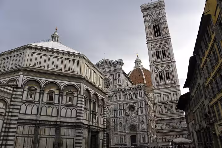Florence Cathedral, Giotto's Bell Tower, and Baptistery against a dramatic sky, showcasing architectural beauty.