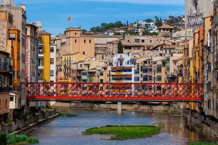 Iconic Eiffel Bridge spans over the Onyar River with Girona's vibrant historic buildings in the background.