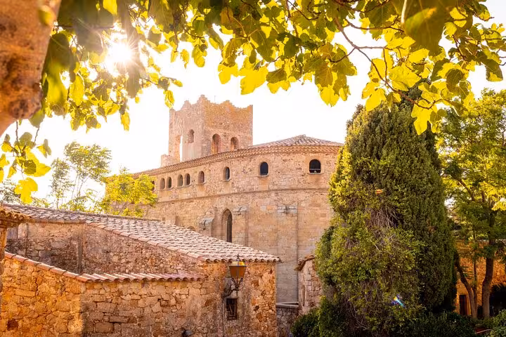 Sunlit medieval architecture surrounded by lush greenery on a private Girona city walk with local guide.