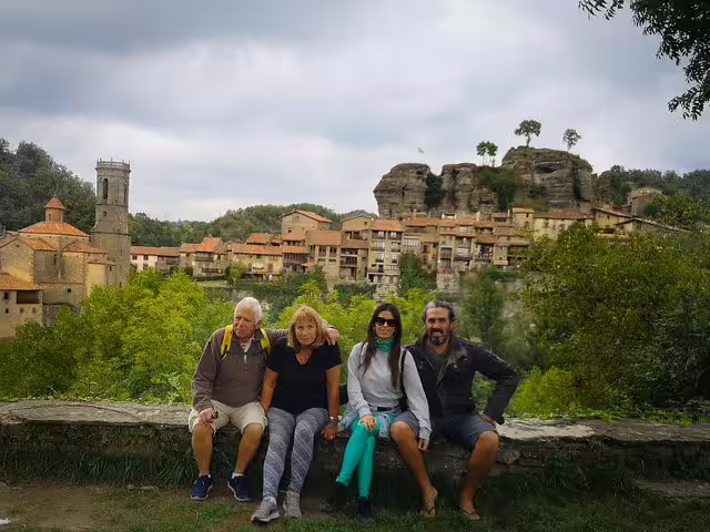 Tourists enjoying a scenic view of a medieval Catalonian village with lush greenery, perfect for a full-day cultural trip.