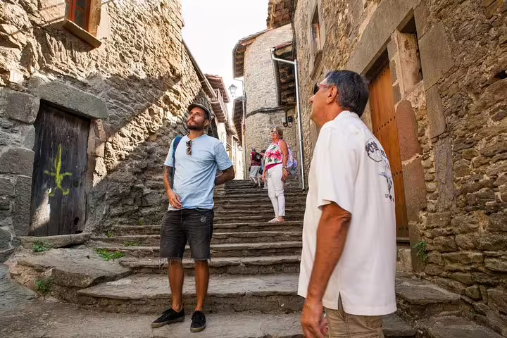Travelers explore the charming stone streets of a medieval village in Catalonia on a guided full-day tour with lunch by a lake.