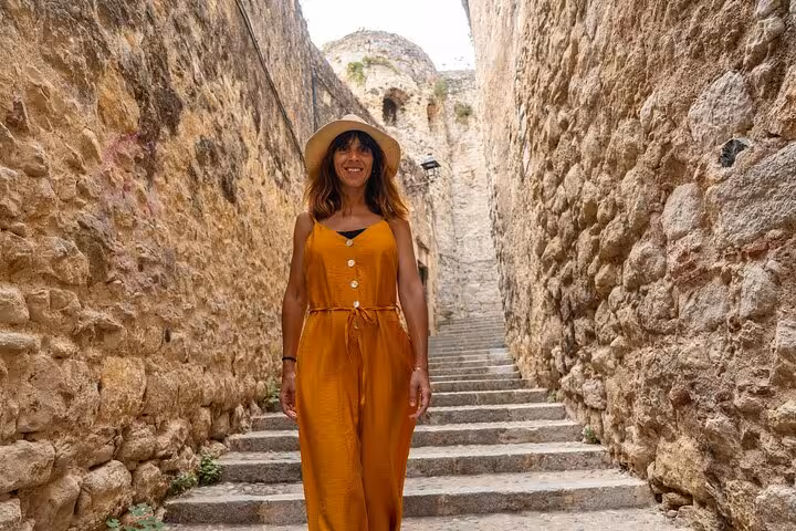Woman in orange dress exploring the historic stone alleyways of Girona on a private guided tour.