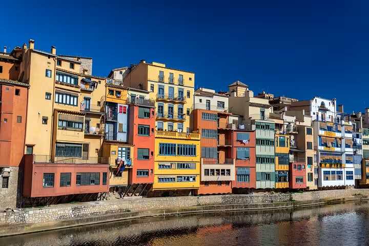 Colorful riverside buildings in Girona under a clear blue sky, featured in a private introductory city walk.