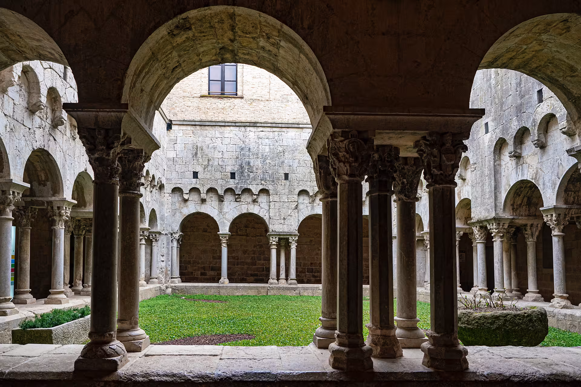 Romanesque cloister in Girona Old Town, stone arches and columns on a full-day tour from Barcelona