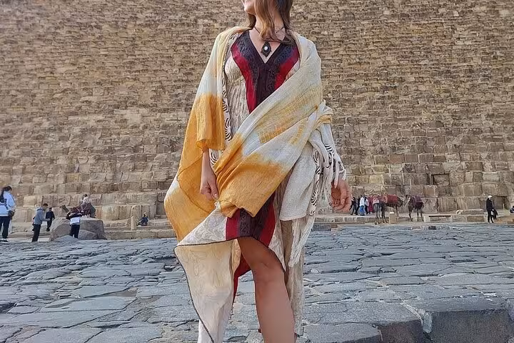Traveler in traditional shawl standing by the Great Pyramid of Giza on a private full-day Cairo tour
