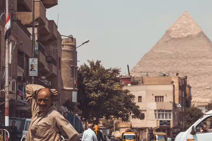 Street scene in Giza with local man and the Great Pyramid in background, part of Cairo day tour to Giza Pyramids