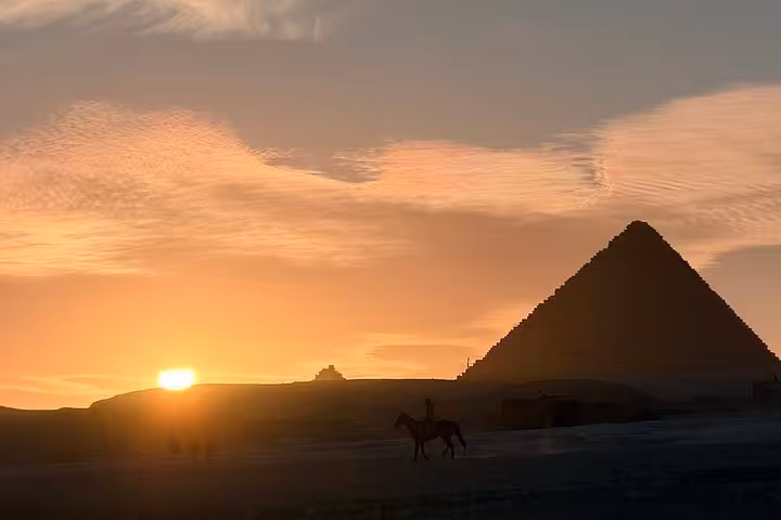 Sunset silhouette of rider by Giza Pyramid on exclusive camel ride and desert bike tour in Cairo desert