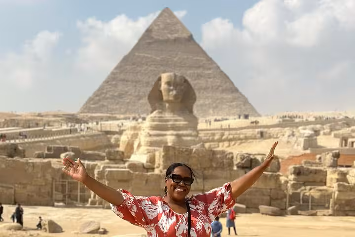 Traveler posing by the Sphinx with Great Pyramid of Giza, Cairo tour featuring camel rides, desert bikes and Nile felucca