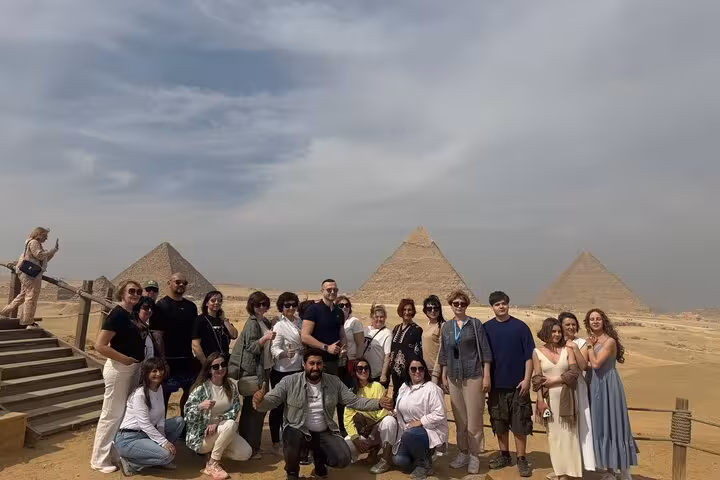 Group overlooking the Giza Plateau with pyramids in background on Cairo tour visiting Giza Pyramids, Museum and bazaar