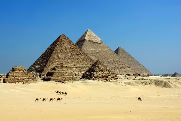 Giza Pyramids panorama with camel caravan in desert, classic stop on Grand Egyptian Museum day tour