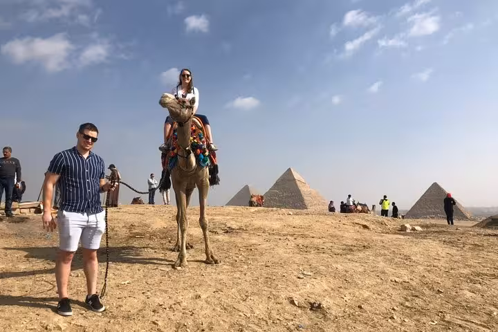 Tourists on a camel ride at the Giza Pyramids plateau on a private tour with lunch in Cairo, Egypt