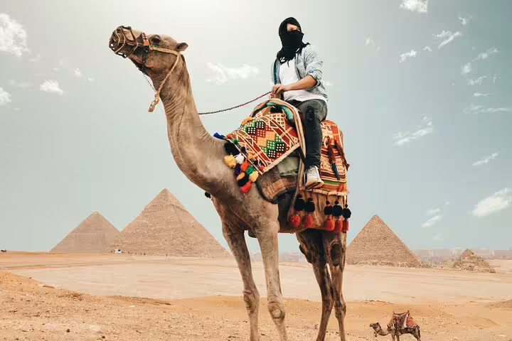 Traveler on a decorated camel ride at Giza Pyramids, Cairo day tour experience before the Egyptian Museum