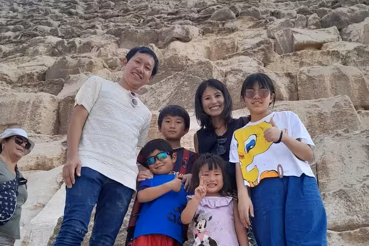 Family photo at the Giza Pyramids stone blocks on a private full-day Cairo tour with camel ride experience
