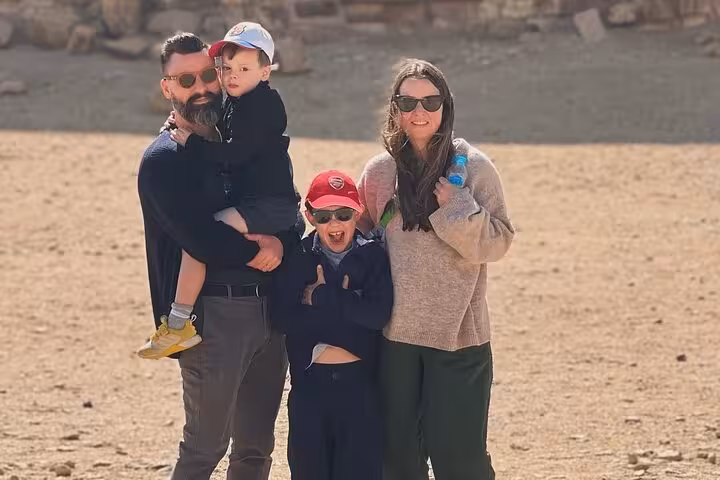 Family photo on the Giza Plateau during a private Cairo day tour featuring pyramids visit and camel ride