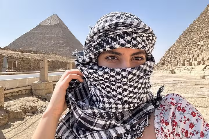 Traveler in keffiyeh at Giza Plateau with Great Pyramid backdrop on half-day Giza Pyramids and Sphinx tour