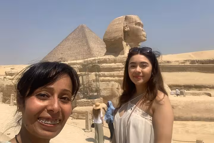 Tourists pose by the Great Sphinx and Giza Pyramid on a Cairo camel ride and lunch tour experience