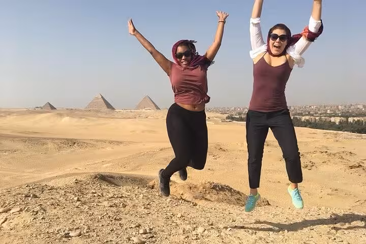 Guests jumping with joy at Giza Plateau viewpoint on VIP all-inclusive pyramids and camel ride tour