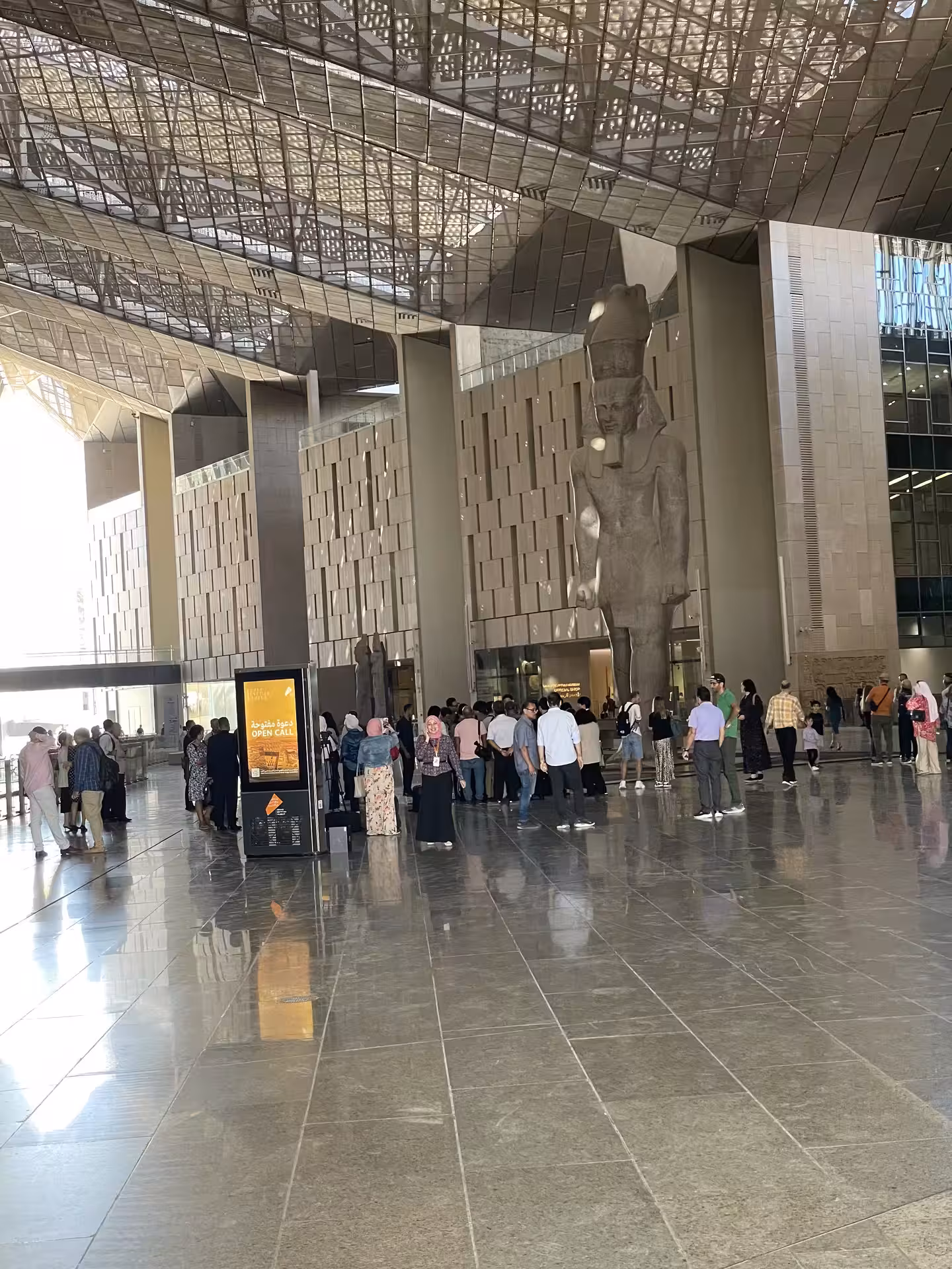 Gran Museo Egipcio en Guiza con gran estatua y visitantes, parada clave del tour día completo desde El Cairo