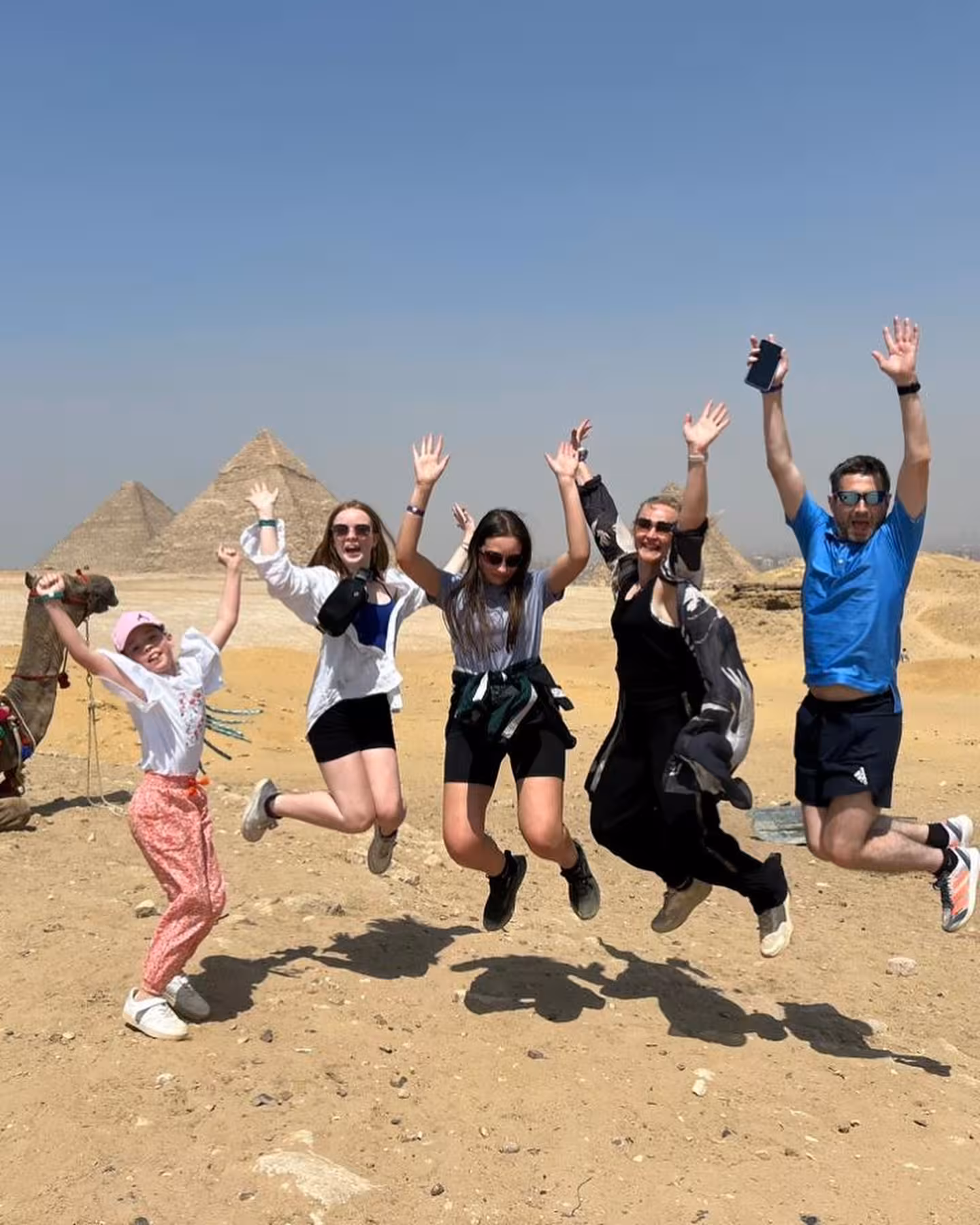 Grupo saltando en el desierto con las Pirámides de Guiza al fondo en excursión de día completo desde El Cairo