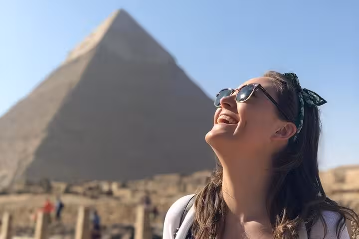 Smiling traveler at the Great Pyramid of Giza on a private Cairo tour with Sphinx visit, camel ride and lunch