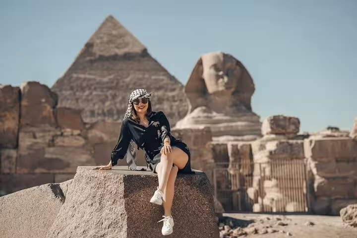 Tourist seated near the Great Sphinx and Giza Pyramid on a VIP all-inclusive Giza tour with camel ride