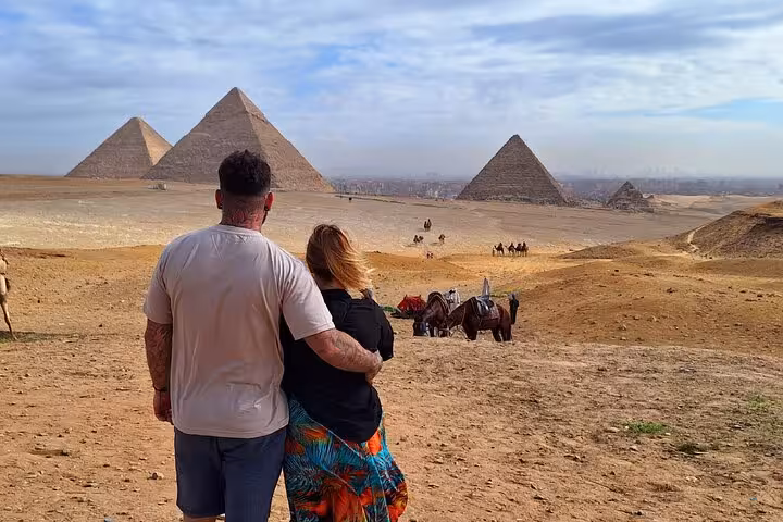 Couple enjoying panoramic view of Giza Pyramids and camels on a private tour with lunch and camel ride included.
