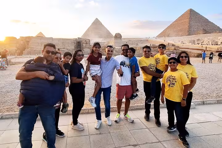 Group of tourists enjoying a sunny day at the Giza Pyramids, perfect for a private tour with camel rides and lunch.