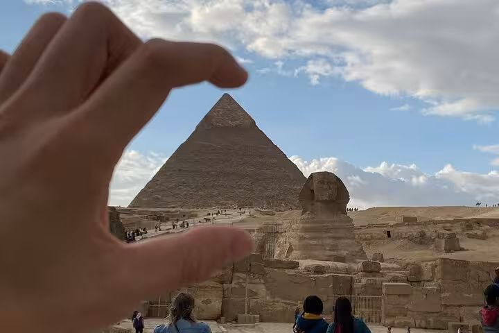 Hand framing the Great Pyramid and Sphinx at Giza on a private tour featuring camel ride and lunch